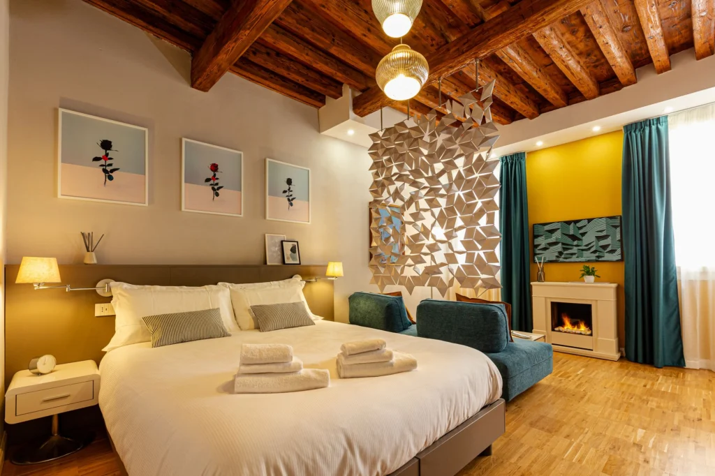 Second bedroom of the Fraivolti apartment with exposed wooden beams, teal curtains and a sculptural room divider