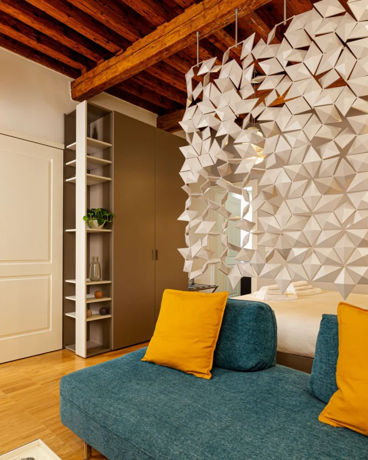 Teal sofa with yellow cushions under the wooden beams of the apartment