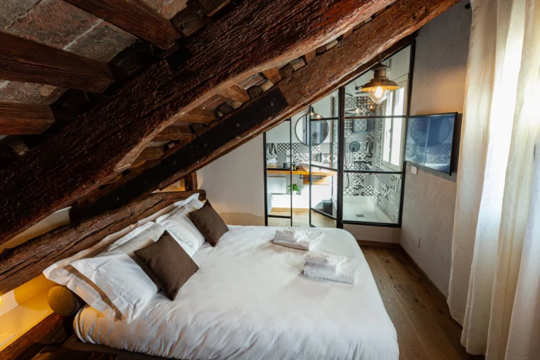 Double bed under the sloping wooden beams of the room
