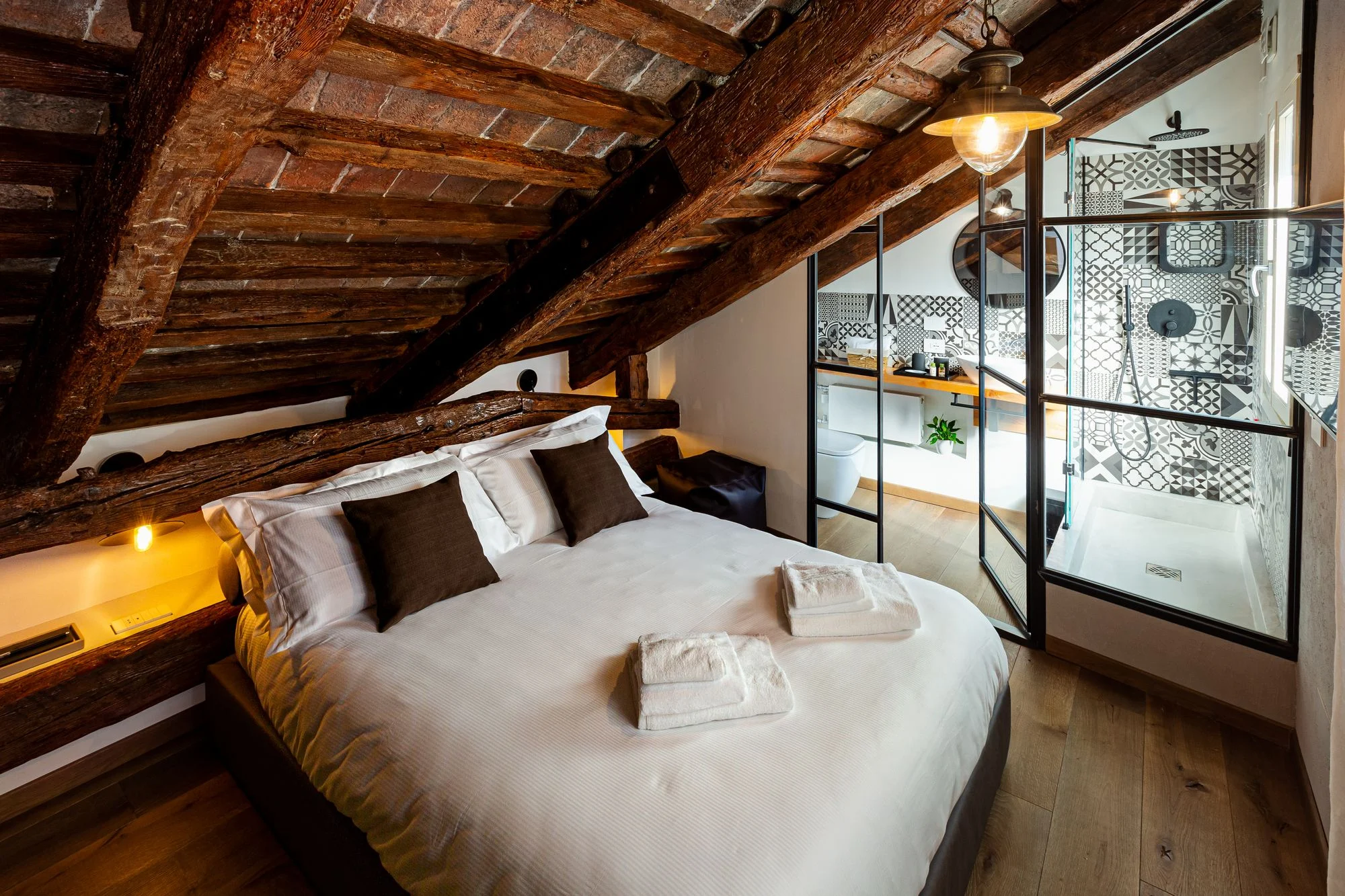 Double room under the roof beams, with the iron-and-glass bathroom wall